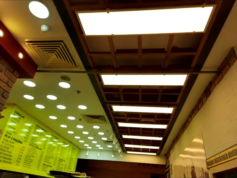 Restoranda ahşap ızgara tavana monte edilmiş LED panel ve spot aydınlatma